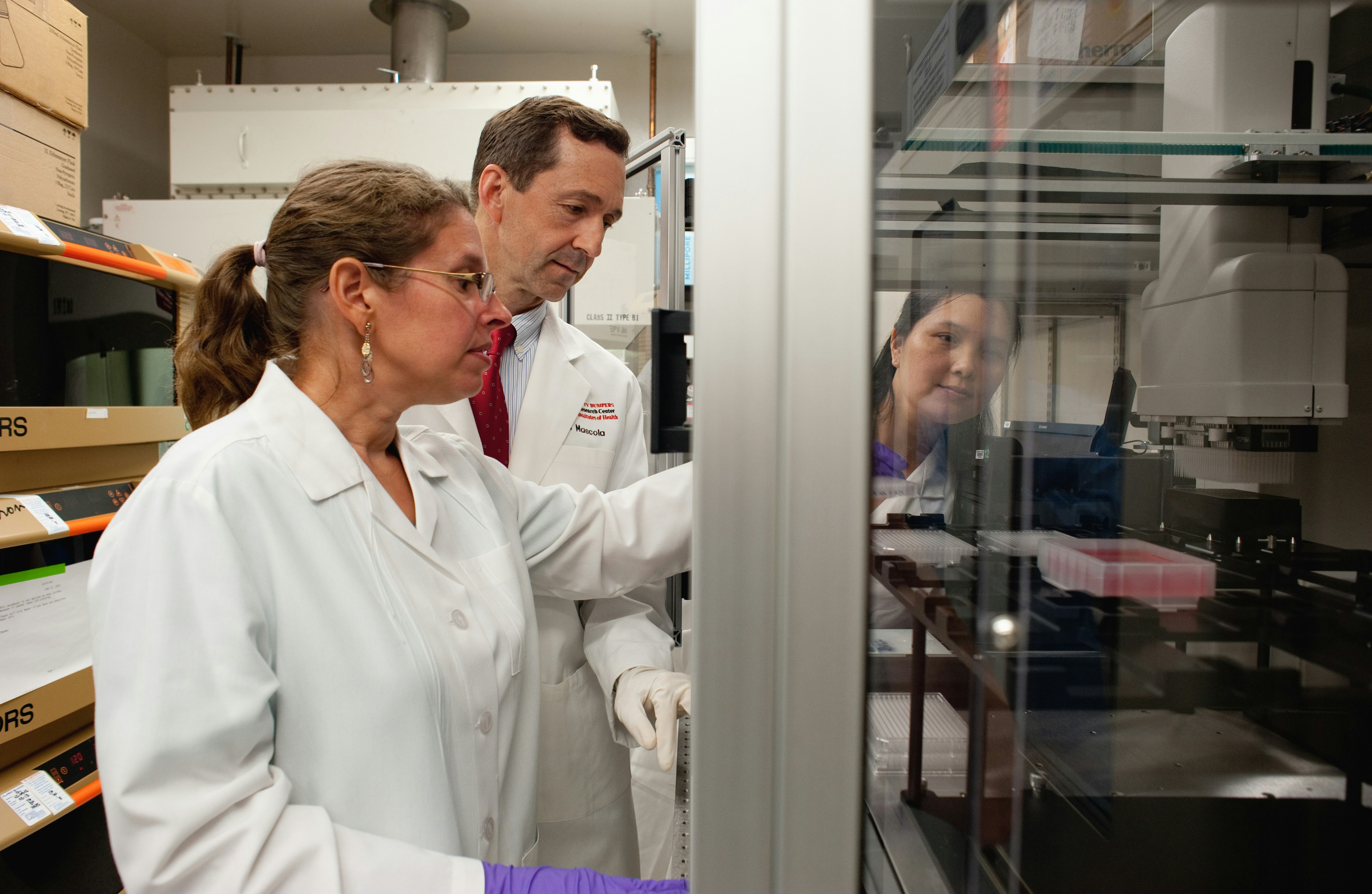 Two researchers in white lab coats observing lab equipment